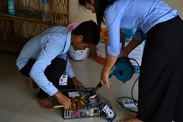 Etudiants utilisant un aspirateur pour nettoyer une tour d'ordinateur